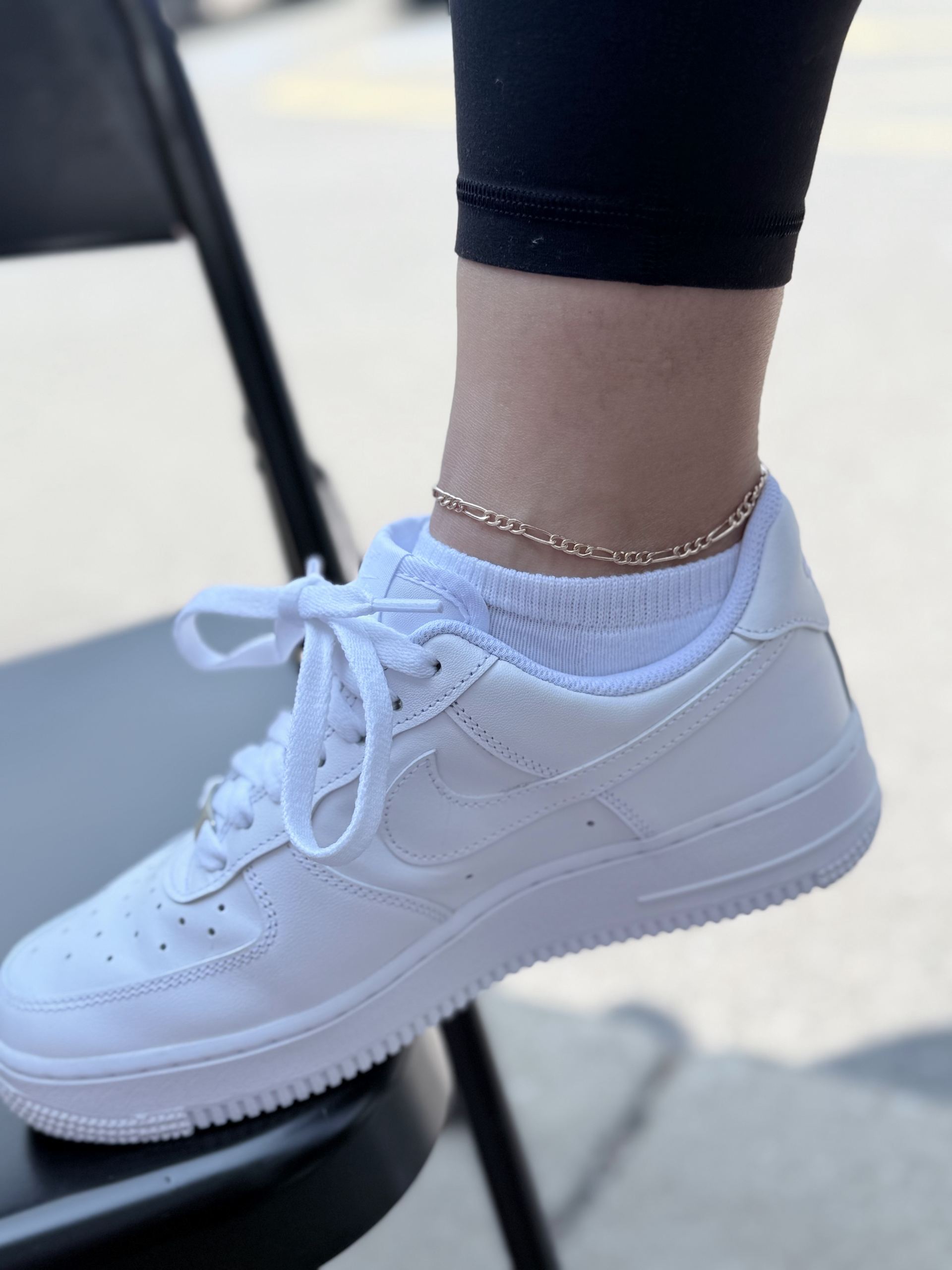 Gold figaro-link chain anklet worn above a white sneaker