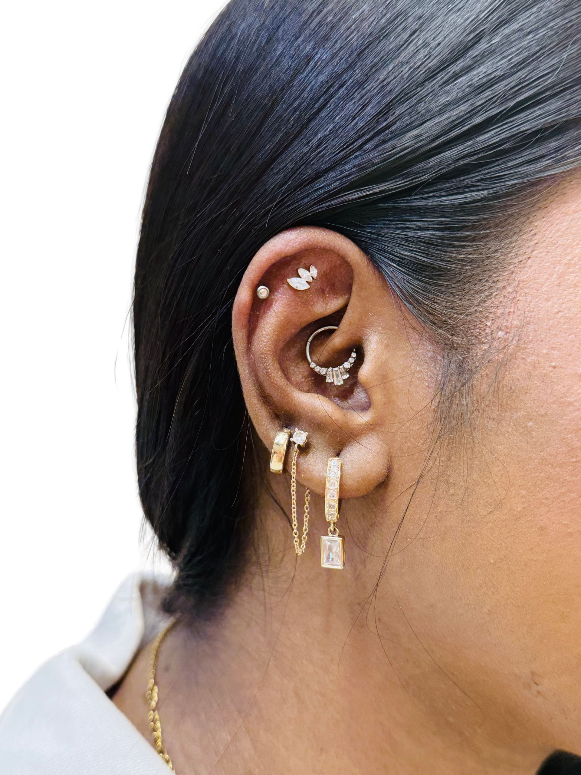 A curated ear stack with multiple gold piercings and a diamond hoop